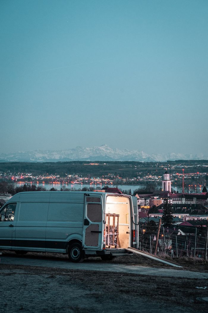 White van parked on a hill with city lights and a scenic horizon at twilight.